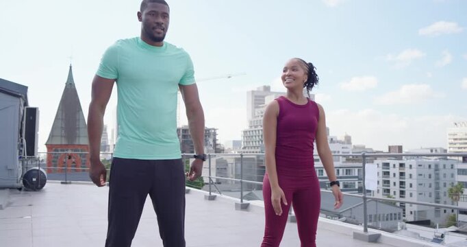 Workout partners in activewear mirroring man signaling, squatting and clapping on roof, trackers