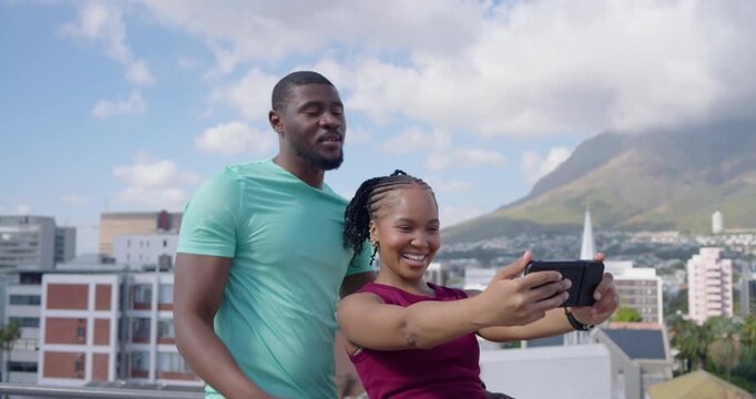 African couple with man coming behind woman, taking selfies on rooftop gym tops reviewing phone