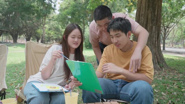 Collaborative Brainstorming Session in Nature: A young team focuses intently on a project, their faces a mixture of concentration and collaboration amidst a verdant outdoor setting.
