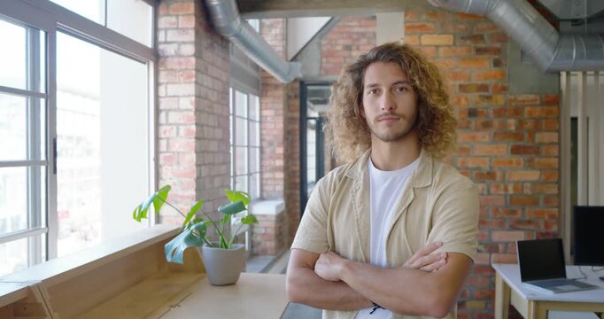 Adult man standing arms crossed loft window camera zoom causing gaze shifting smiling and laughing
