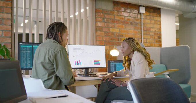 Left male starting by gesturing at charts right woman pointing third joining reviewing data at desk