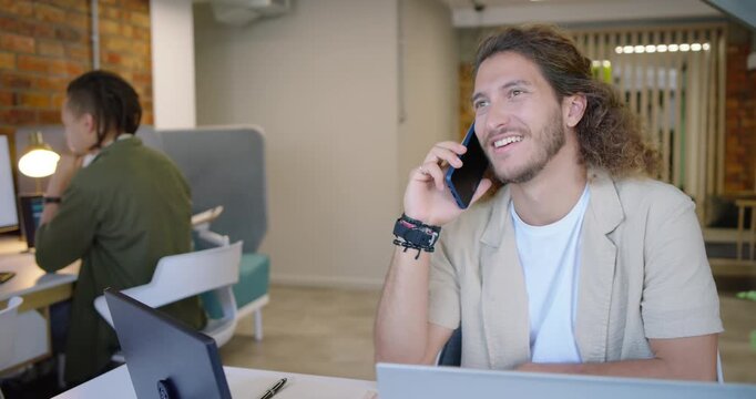 Diverse coworkers watching man answering incoming call in office, gesturing with blue phone