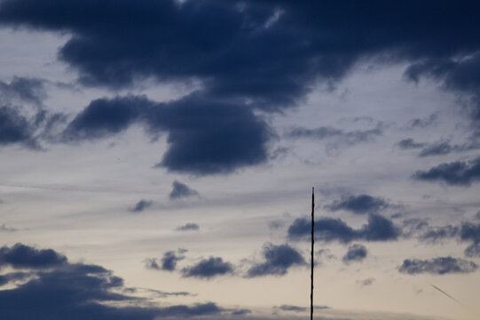 Dramatic Evening Sky with Dark Clouds and Thin Antenna Silhouette. Atmospheric Dusk Cloudscape with Communication Tower.