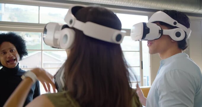 Diverse team trying VR sets in studio woman stepping donning headset, guide guiding with tablet