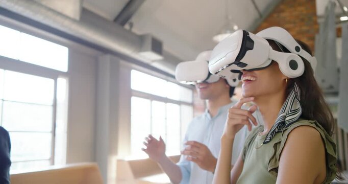 Diverse coworkers following presenter gesture, donning white VR headsets for product demo in loft