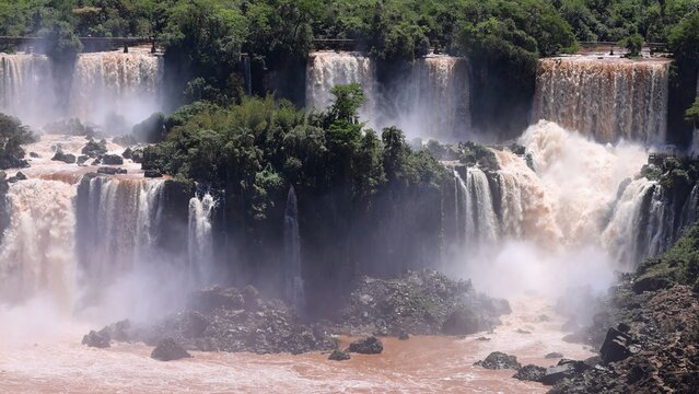 Aerial view of Iguazu Falls featuring cascading water, lush tropical vegetation, and mist rising from the river in Foz do Iguacu, State of Parana, Brazil.