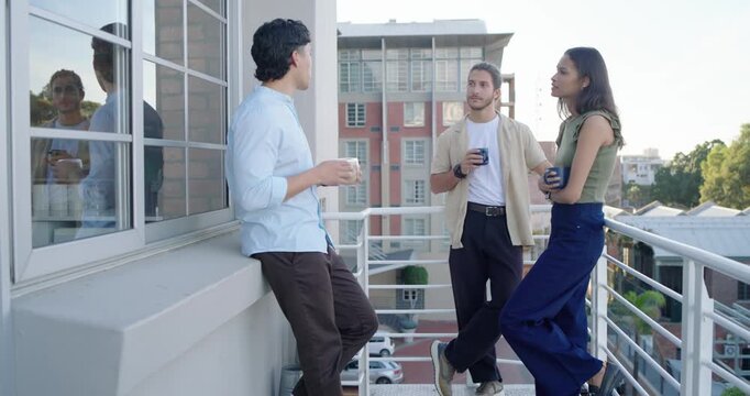 Diverse friends on balcony catching up as left man leaning on ledge speaking gesturing sipping mugs