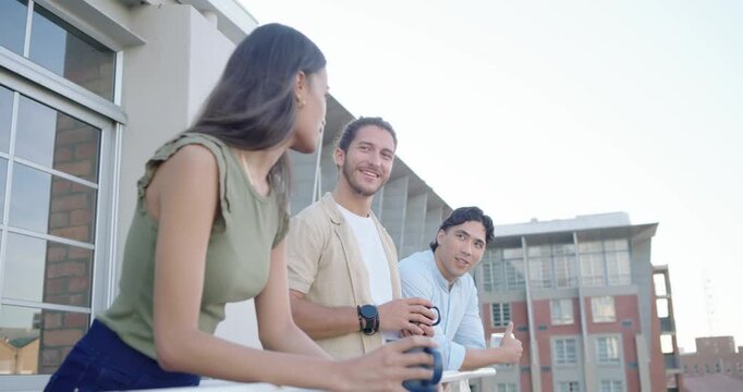 Diverse friends leaning on balcony rail with cups, woman starting chat, center man pointing to view