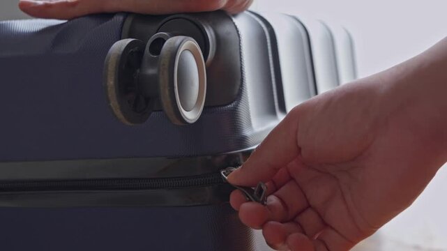 Close Up of a Hand Opening the Zipper of a Blue Suitcase