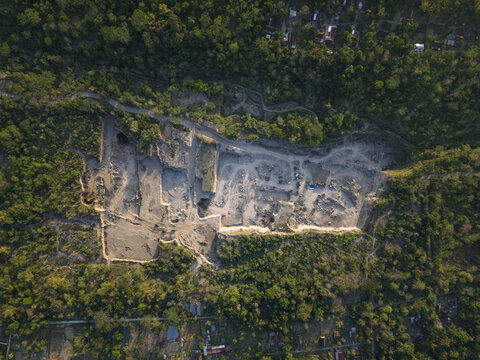 Aerial view of the Sand and Stone Quarry showing excavated terrain, rocky surfaces, and surrounding dense tropical forest in Manisrenggo, Central Java, Indonesia.