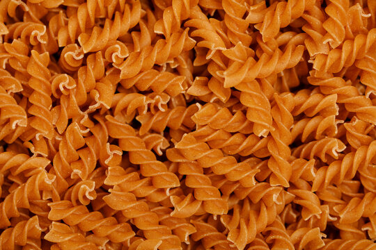 Close up shot of dry whole wheat fusilli pasta forming a textured background.