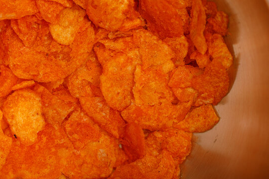 Crispy crunchy orange potato chips piled high creating a delightful snack background.
