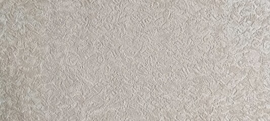 Fototapeta premium Close up of beige textured wallpaper with an intricate swirling relief pattern resembling abstract organic foliage. Background or interior design concept.