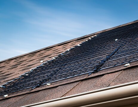 close up of asphalt roof shingles and metal gutter guard mesh