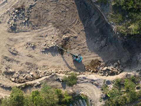 Aerial view of a sand and stone quarry with an excavator working on the ground in Manisrenggo, Central Java, Indonesia.