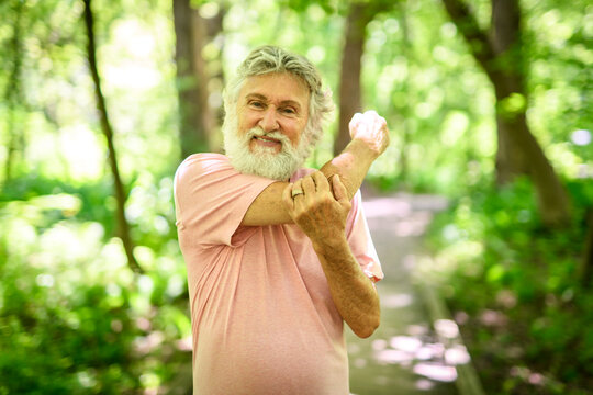 Nice active 70s senior men runner or fast walk in a park doing some stretching