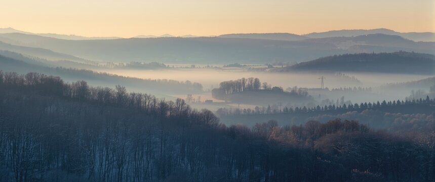 Misty spring morning with soft snow highlights and broad valley view for copy space