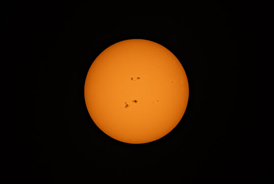 The orange coloured afternoon sun glowing with massive sunspots using a homemade solar filter against a black background over Canada June 29, 2026 