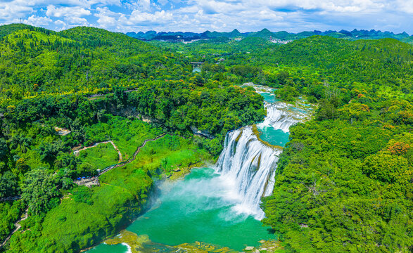 Aerial view of Huangguoshu Waterfall in Anshun, Guizhou, China, surrounded by lush green tropical forest and turquoise river water