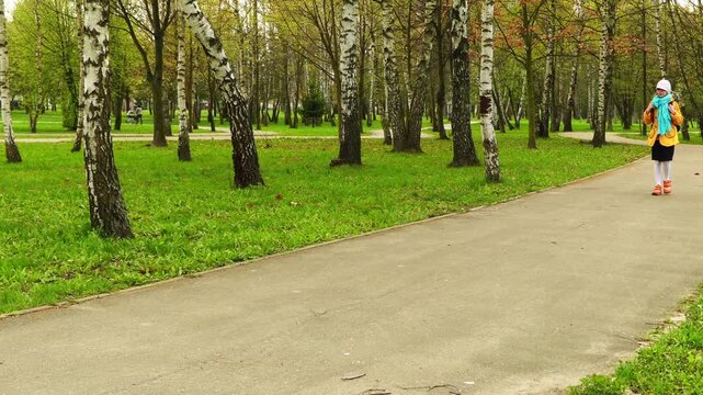girl in yellow coat and backpack goes to school