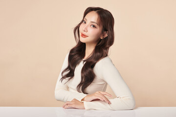 Naklejka premium A beautiful young Asian woman with clean, fresh skin against a beige background. Skincare, facial treatment, cosmetology, beauty, and spa. An elegant portrait of an Asian woman.