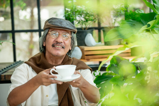 Smiling elderly man enjoying quiet leisure time with coffee among beautiful houseplants representing positive aging comfort and sustainable home lifestyle.