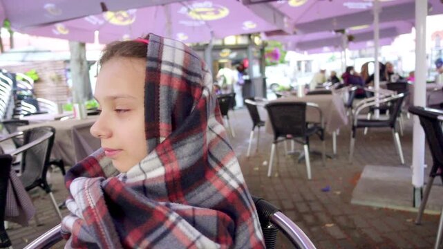 Little beautiful girl in a warm plaid in cafe