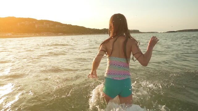 Little beautiful girl plays in warm summer sea