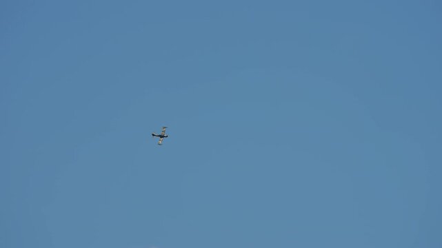 Vintage military jet approaching head on, classic twin engine jet trainer from the 1950s era flying low with wingtip fuel tanks, straight wing aircraft against a clear blue sky
