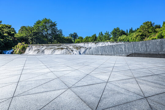 Empty plaza and cascading waterfall under clear blue sky in Guizhou, China