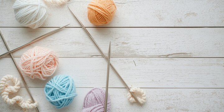 Top perspective of knitting needles paired with wool balls on weathered white wooden table including copy space