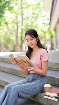 Relaxed young student woman reading a book in university campus.