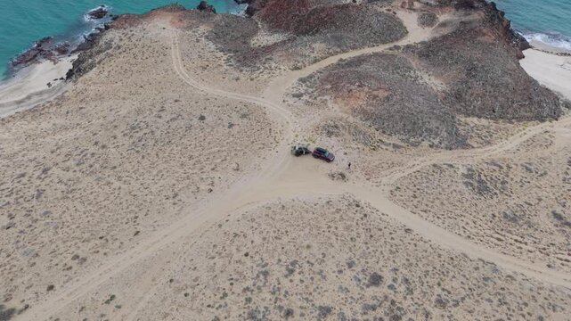 Camping on a cliff with a teardrop trailer and suv overlooking the pacific ocean during an overland trip in baja california