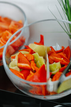 Colorful pepper pieces fill clear bowls beside herbs, suggesting fresh meal prep in vibrant kitchen light
