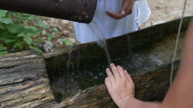 Two little girls drinking water from spring