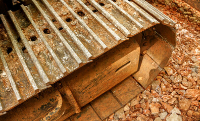 Close up view of muddy steel excavator tracks on gravel terrain. Perfect for construction manuals, machinery advertising, and industrial blog articles. © YuliiaKettu