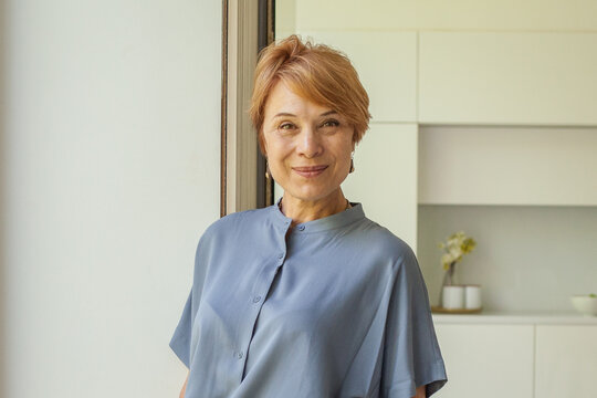Attractive smiling 55 years old woman at home portrait