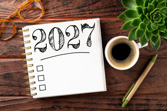 New year resolutions 2027 on desk. 2027 goals list with notebook, coffee cup, plant on wooden table. Resolutions, plan, goals, action, checklist, idea concept. New Year 2027 resolutions. Copy space