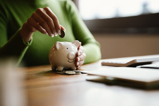 A close-up image of people dropping coins into a piggy bank, a symbol of saving and future financial security.