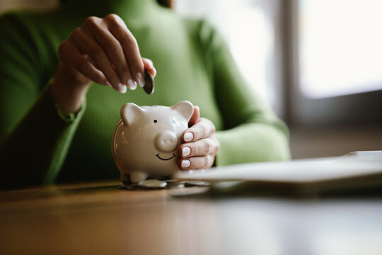 A close-up image of people dropping coins into a piggy bank, a symbol of saving and future financial security.