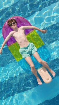 Teen boy floating pool inflatable mattress sunglasses relaxing sunny day vacation summer leisure top view lifestyle vertical