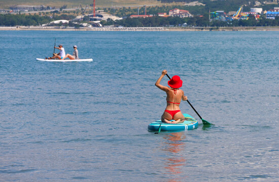 young women in red bikini  riding  on sup surfing in the sea at sumer time