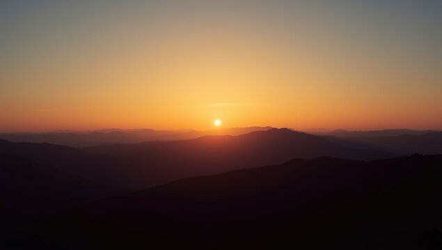 Sunrise over rolling mountains in a golden sky