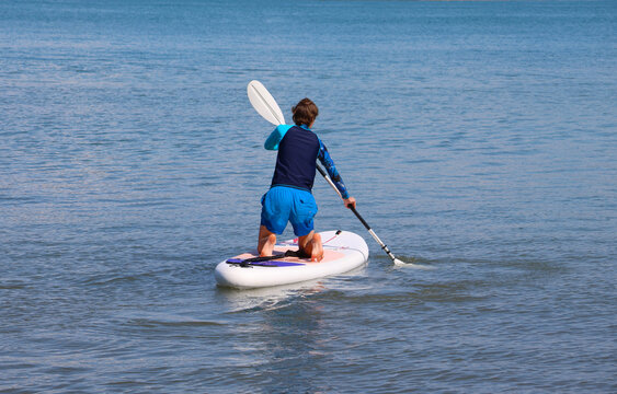 young men  riding  on sup surfing in the sea at sunset