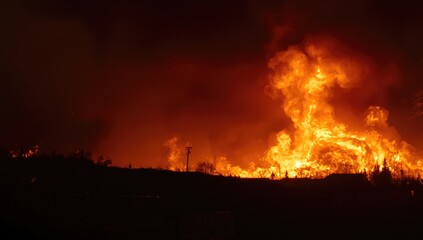 Fototapeta premium Wildfire flames engulfing a landscape at night