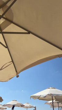 Beach umbrellas and sun loungers beside the sea on a sunny day, relaxing coastal vacation, summer travel, seaside leisure, holiday destination, ocean escape.