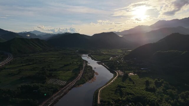 Cinematic drone footage flying over an emerald river valley surrounded by dense tropical vegetation and mountainous landscape in central Vietnam.
