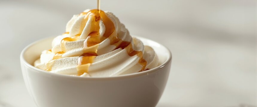 White bowl filled with light whipped cream and glossy vanilla syrup