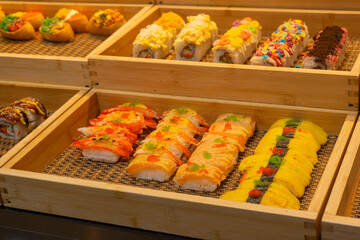 Assorted nigiri and maki sushi in modern fusion style, bright orange and yellow colors, representing a diverse Japanese buffet layout used for catering service © Arnepi