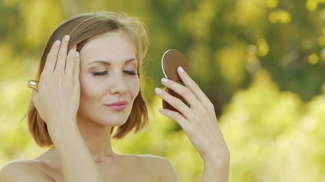 Young beautiful woman puts lipstick on lips